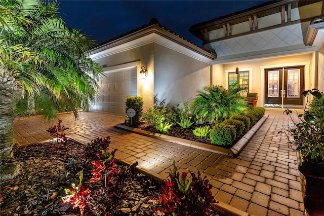 patio at twilight featuring french doors and a garage