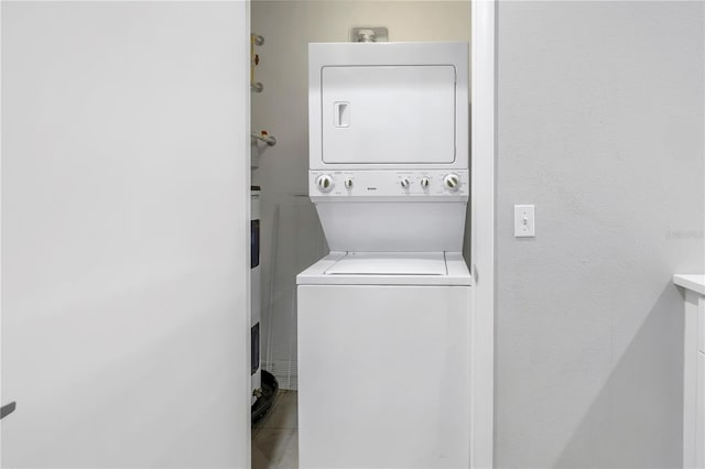 clothes washing area featuring tile floors and stacked washer / dryer