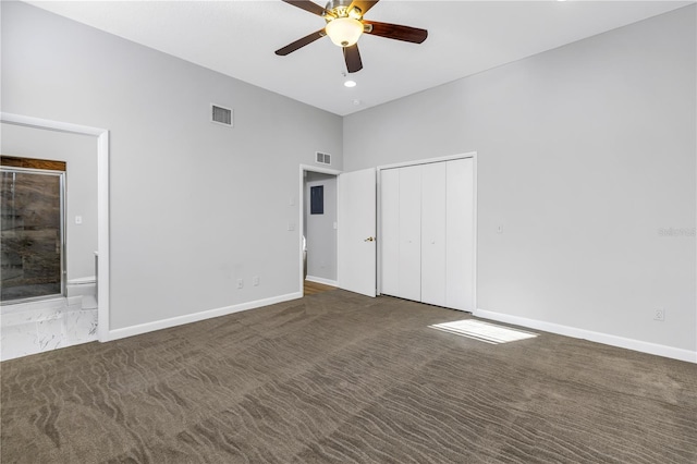 spare room featuring dark colored carpet, ceiling fan, and a towering ceiling