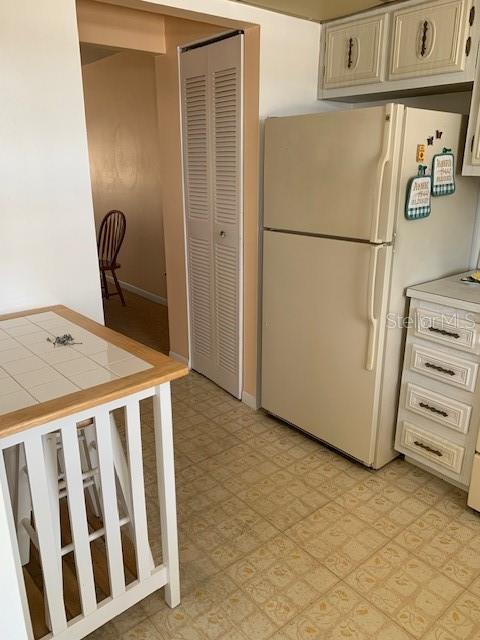 kitchen featuring white refrigerator, tile counters, and light tile floors