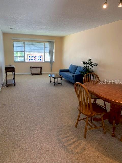 dining area featuring light carpet and a textured ceiling