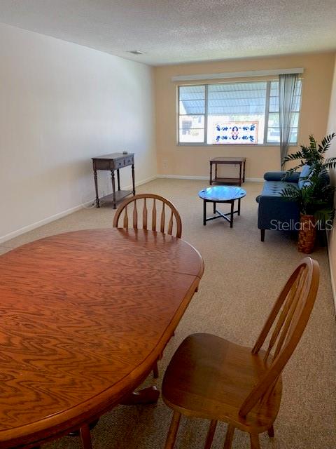 carpeted dining space with a textured ceiling