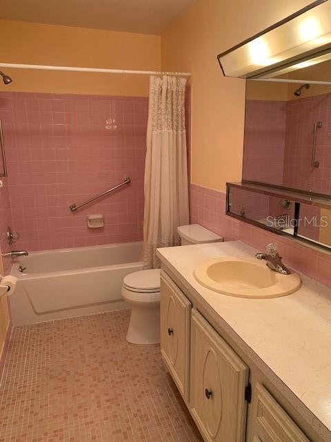 full bathroom featuring toilet, shower / bath combo, oversized vanity, and tile flooring