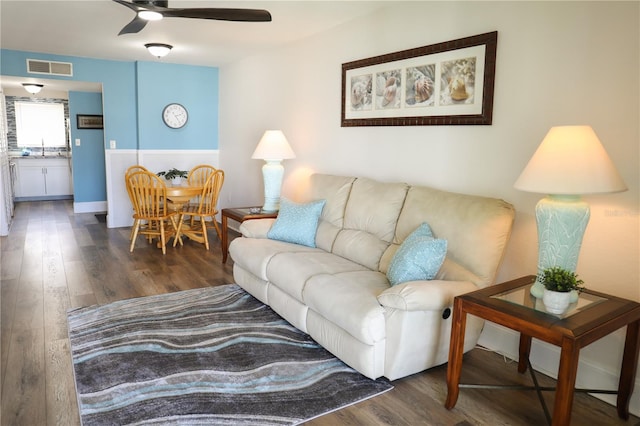 living room featuring ceiling fan, sink, and dark wood-type flooring