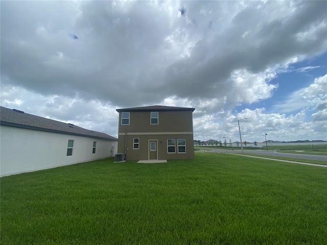 rear view of house with a lawn and cooling unit