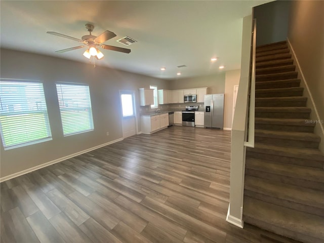 unfurnished living room with dark hardwood / wood-style floors, ceiling fan, and sink