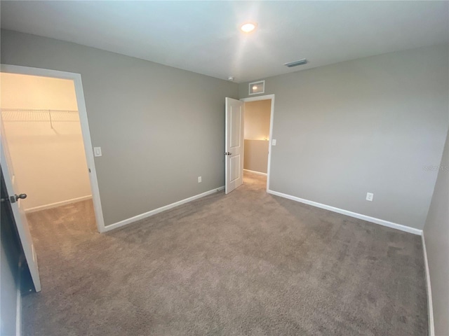 unfurnished bedroom with carpet flooring, a spacious closet, and a closet