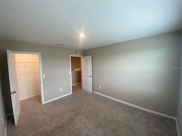 unfurnished bedroom with carpet floors, a spacious closet, and a closet