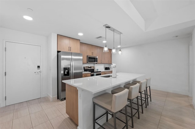 kitchen with appliances with stainless steel finishes, light tile patterned floors, hanging light fixtures, and sink