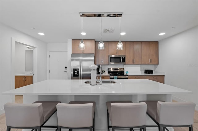 kitchen featuring appliances with stainless steel finishes, a kitchen breakfast bar, and decorative light fixtures