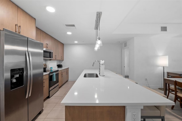 kitchen with stainless steel appliances, pendant lighting, light tile patterned floors, a breakfast bar area, and sink