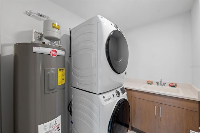 laundry area featuring electric water heater, sink, stacked washer and clothes dryer, and cabinets