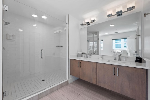 bathroom with double sink vanity, a shower with shower door, and tile patterned flooring