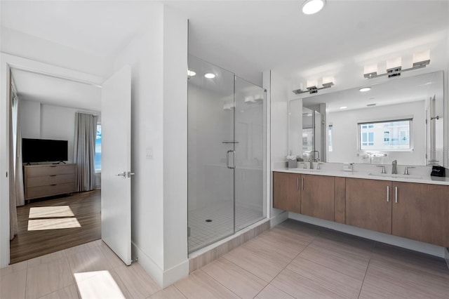 bathroom featuring double sink vanity, hardwood / wood-style flooring, and a shower with door