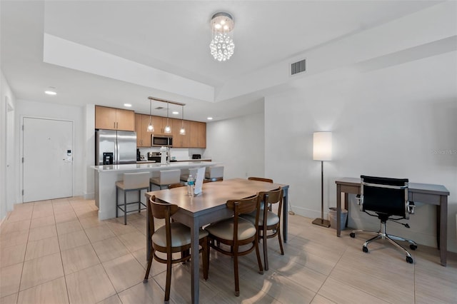 tiled dining area featuring a tray ceiling and an inviting chandelier