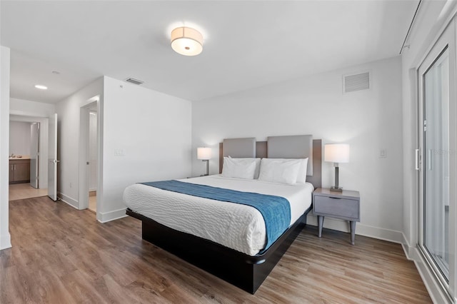 bedroom featuring ensuite bath and hardwood / wood-style flooring