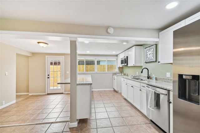 kitchen featuring appliances with stainless steel finishes, white cabinetry, light stone countertops, light tile patterned floors, and sink