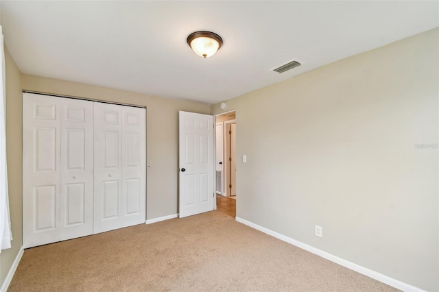 unfurnished bedroom with light carpet and a closet