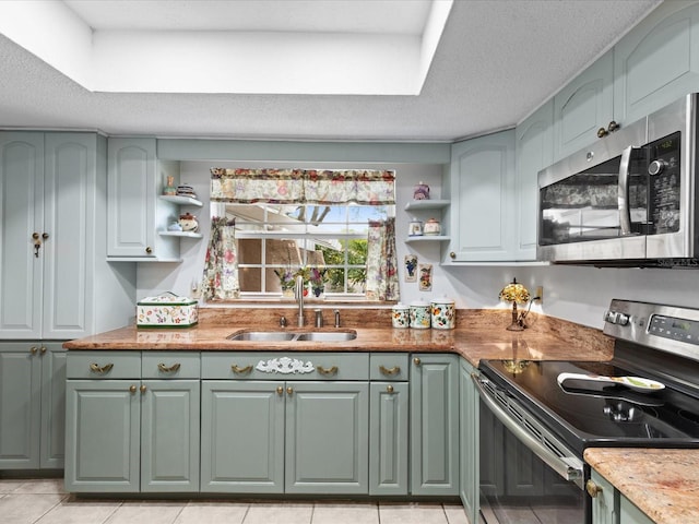 kitchen featuring stainless steel appliances, a textured ceiling, sink, and light tile floors