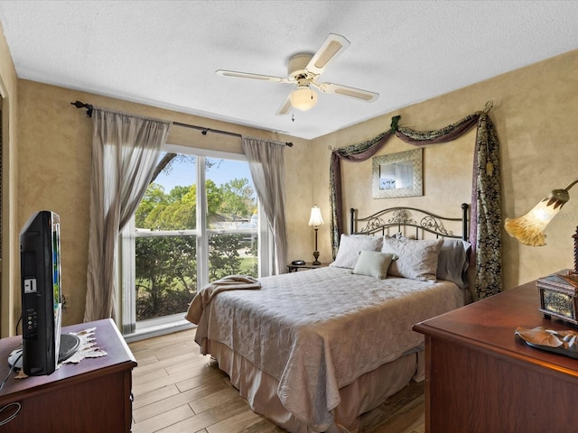 bedroom featuring a textured ceiling, multiple windows, ceiling fan, and light wood-type flooring