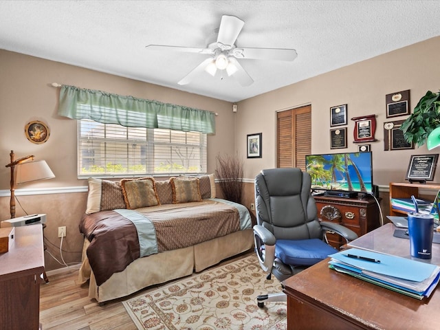 bedroom with a textured ceiling, a closet, ceiling fan, and light wood-type flooring