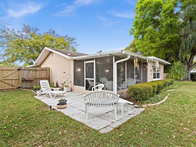 rear view of property with a lawn, a patio, and a sunroom