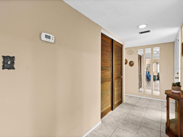 hallway with a textured ceiling and light tile flooring