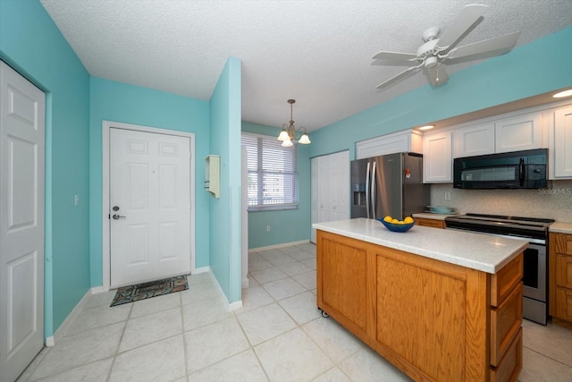 kitchen featuring light tile floors, ceiling fan with notable chandelier, stainless steel appliances, a center island, and hanging light fixtures