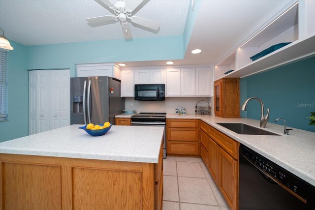 kitchen with light tile floors, black appliances, white cabinets, sink, and a center island