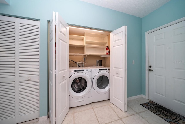 washroom with washer and clothes dryer, washer hookup, light tile floors, and a textured ceiling