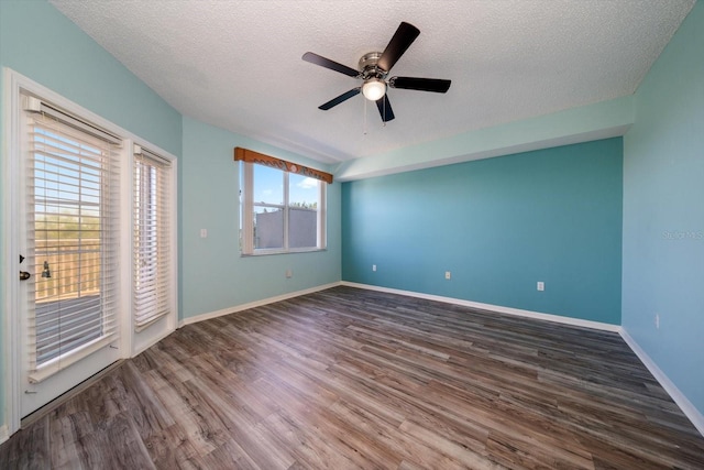 empty room with ceiling fan, dark wood-type flooring, and a textured ceiling