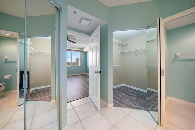 bathroom with tile flooring, a textured ceiling, toilet, and ceiling fan