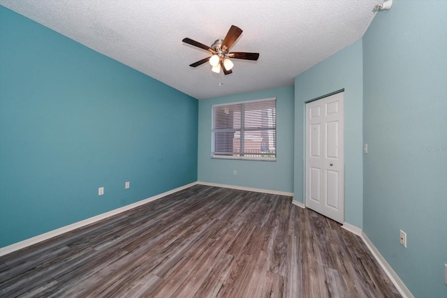 unfurnished bedroom with ceiling fan, a closet, dark hardwood / wood-style floors, and a textured ceiling