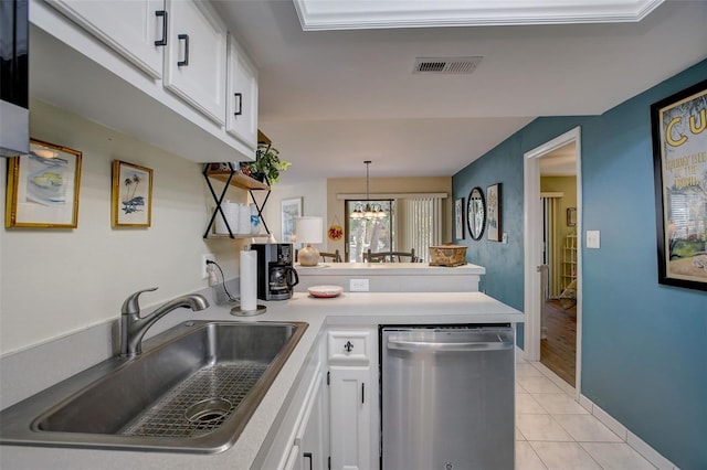 kitchen featuring light tile patterned floors, a peninsula, a sink, white cabinets, and stainless steel dishwasher