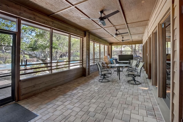 unfurnished sunroom with wood ceiling and a ceiling fan