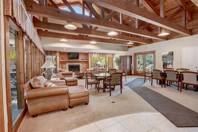 living room with high vaulted ceiling, light tile patterned flooring, light carpet, a brick fireplace, and beamed ceiling