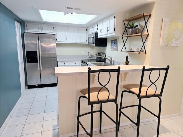 kitchen with appliances with stainless steel finishes, visible vents, a peninsula, and light tile patterned floors