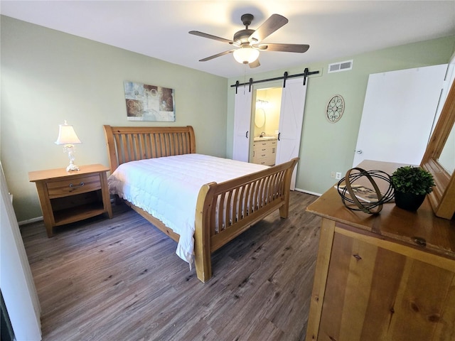 bedroom featuring a barn door, visible vents, baseboards, a ceiling fan, and dark wood-style floors