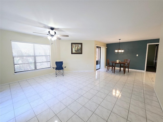 interior space with ceiling fan with notable chandelier, light tile patterned flooring, and baseboards