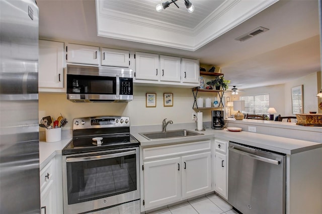 kitchen featuring a tray ceiling, stainless steel appliances, light countertops, visible vents, and a sink