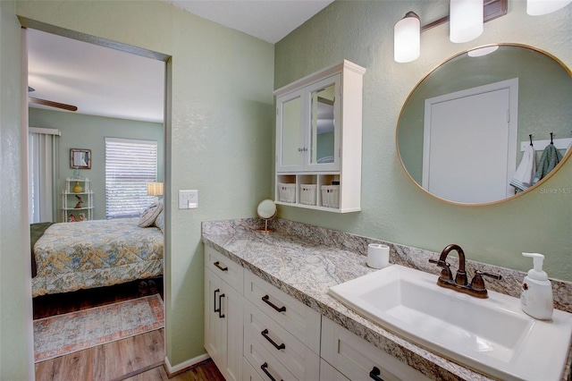 bathroom with a textured wall, connected bathroom, vanity, and wood finished floors