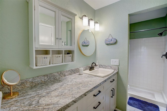 bathroom with toilet, a stall shower, vanity, and a textured wall