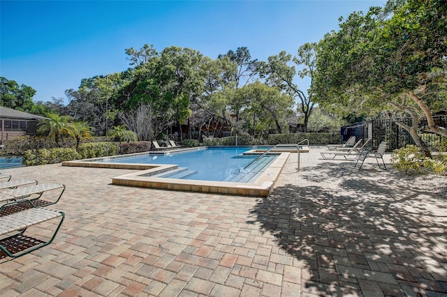 community pool with a patio area and fence