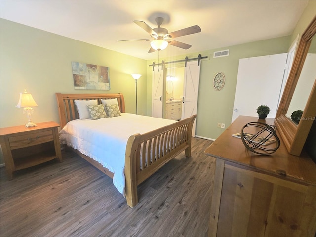 103 Cypress Pond Rd Unit 103, Palm Harbor, FL 34683 - bedroom featuring ensuite bath, a barn door, visible vents, a ceiling fan, and dark wood-type flooring