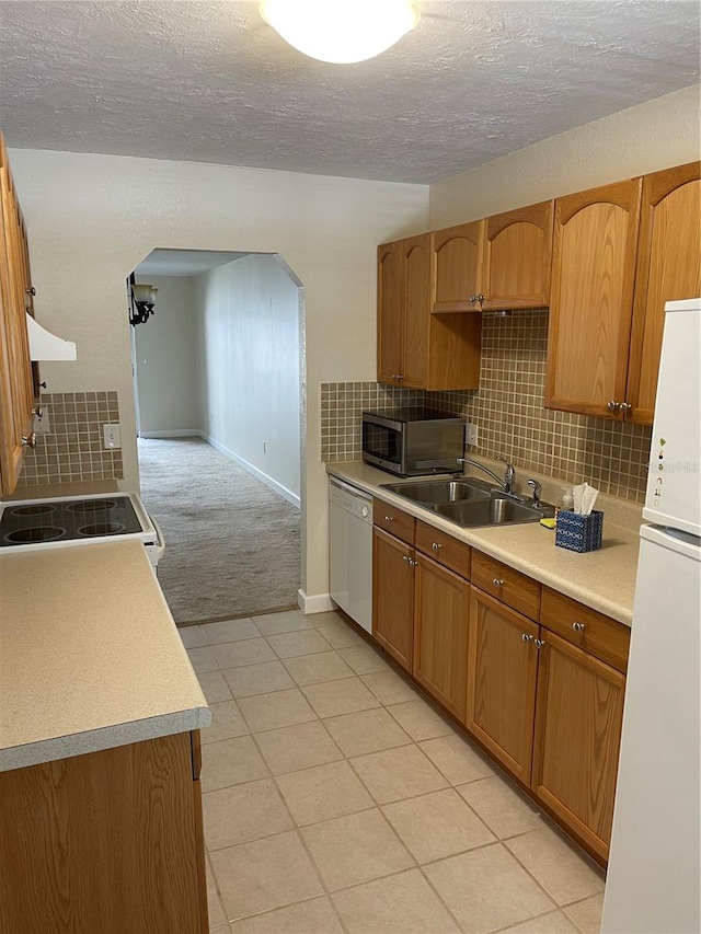 kitchen with decorative backsplash, light tile patterned flooring, white appliances, ventilation hood, and sink