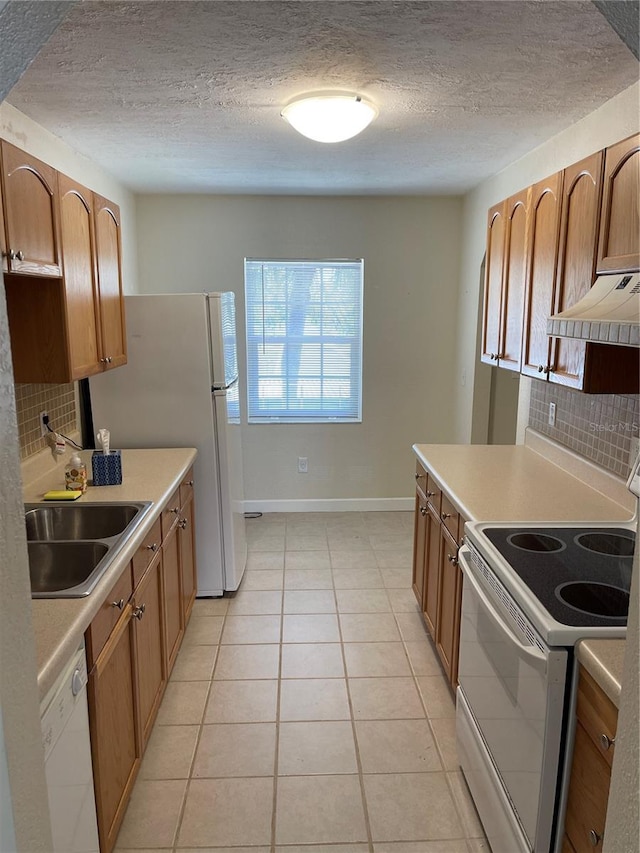 kitchen with sink, light tile patterned floors, white appliances, a textured ceiling, and decorative backsplash