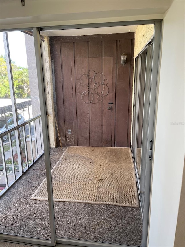 doorway with wood walls and carpet