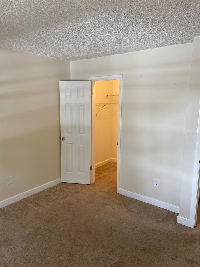 carpeted empty room with a textured ceiling