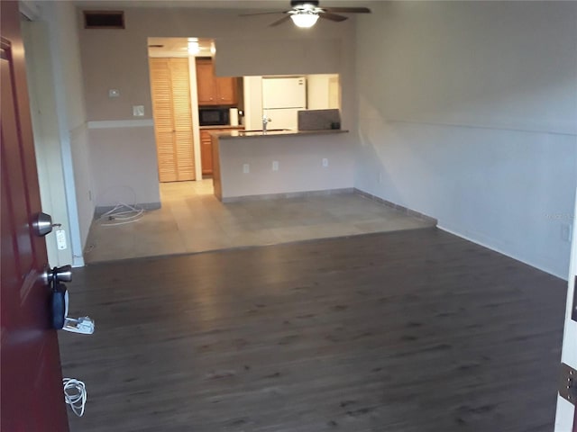 unfurnished living room with a sink, wood finished floors, visible vents, and ceiling fan