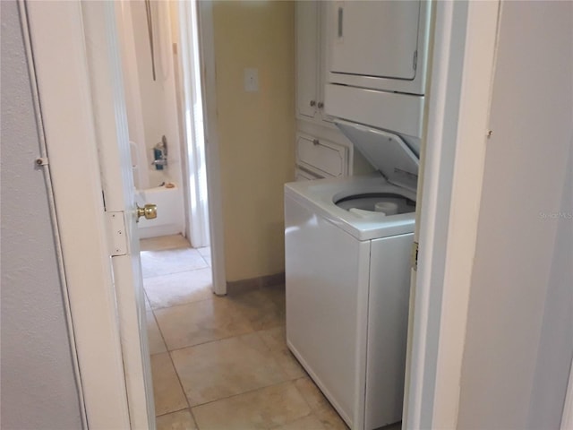 washroom with light tile patterned floors, stacked washer and clothes dryer, and laundry area